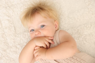 Photo of Cute baby lying on beige carpet at home, top view