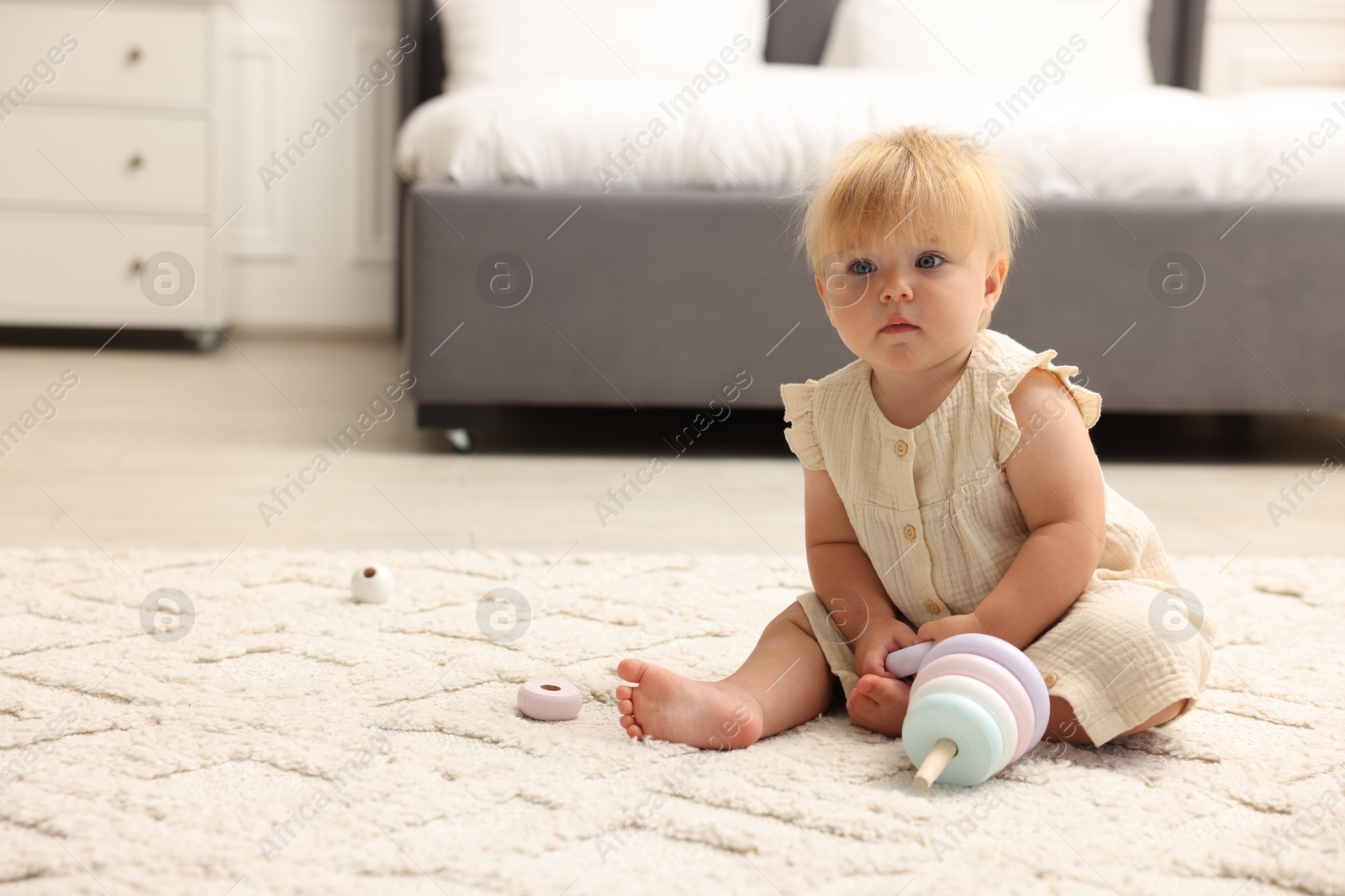 Cute baby girl in dress playing with toy on floor at home. Space for text Photo of Cute baby girl in dress playing with toy on floor at home. Space for text