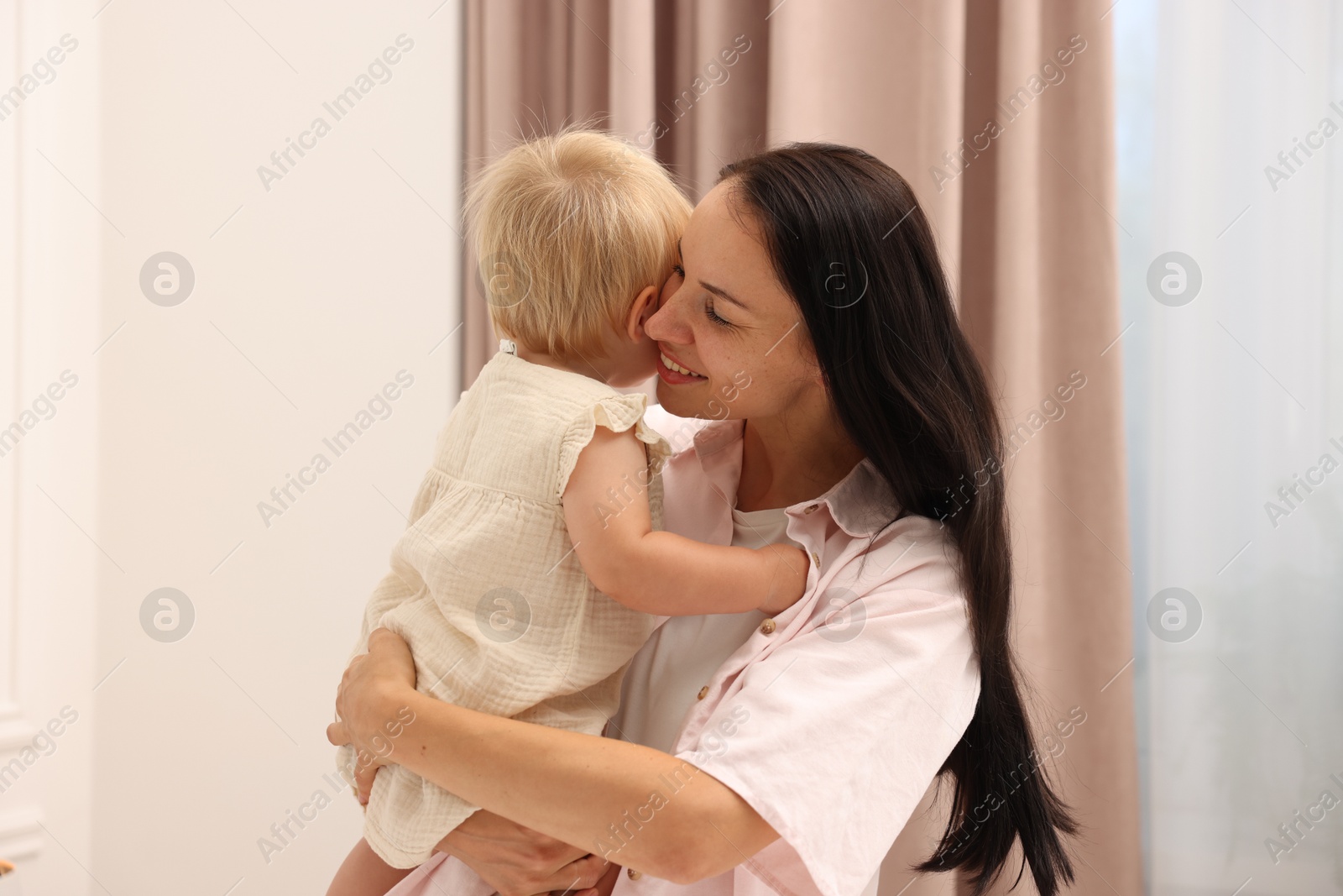 Photo of Smiling mother with her cute baby girl at home