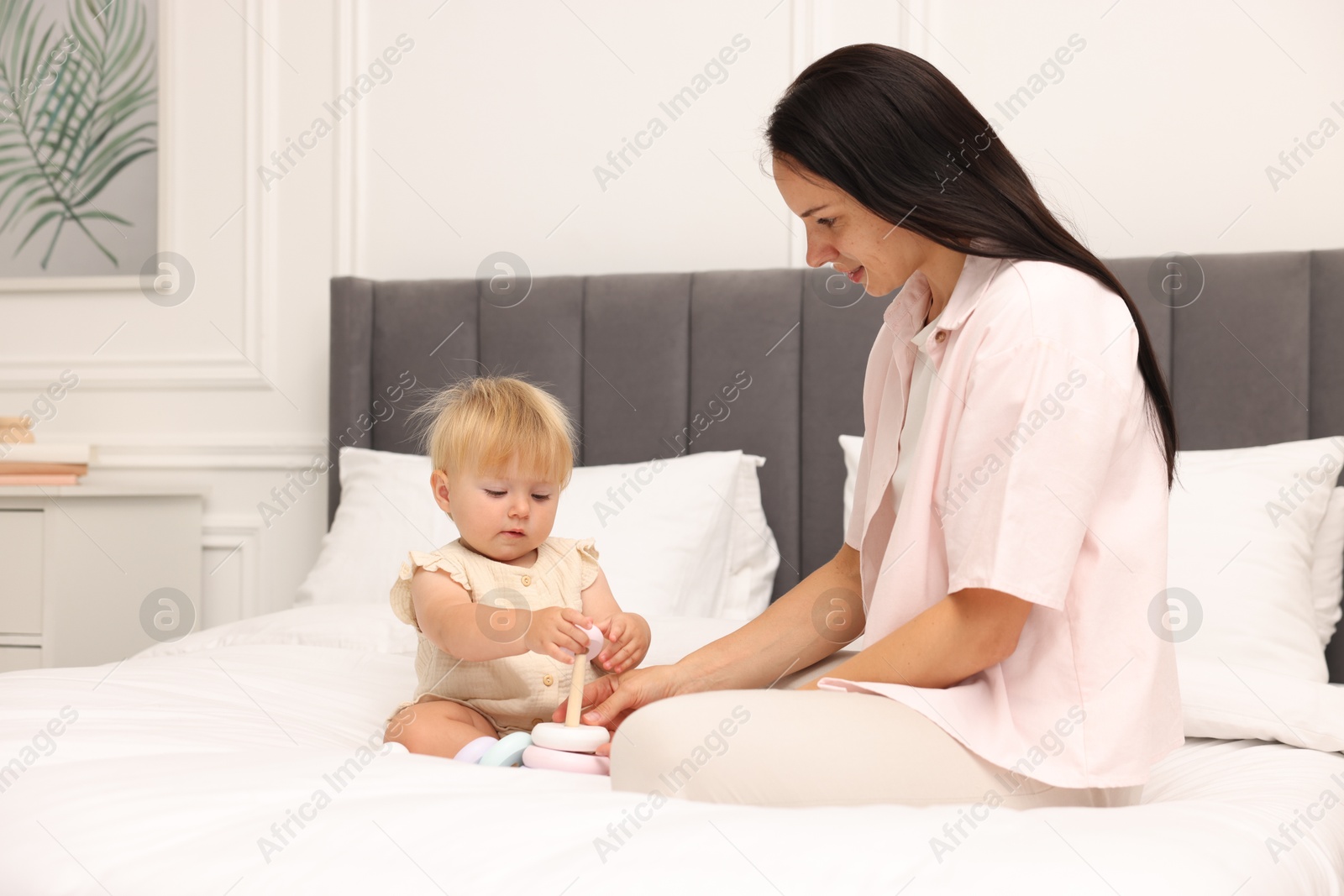 Mother playing with her cute baby girl on bed at home Photo of Mother playing with her cute baby girl on bed at home