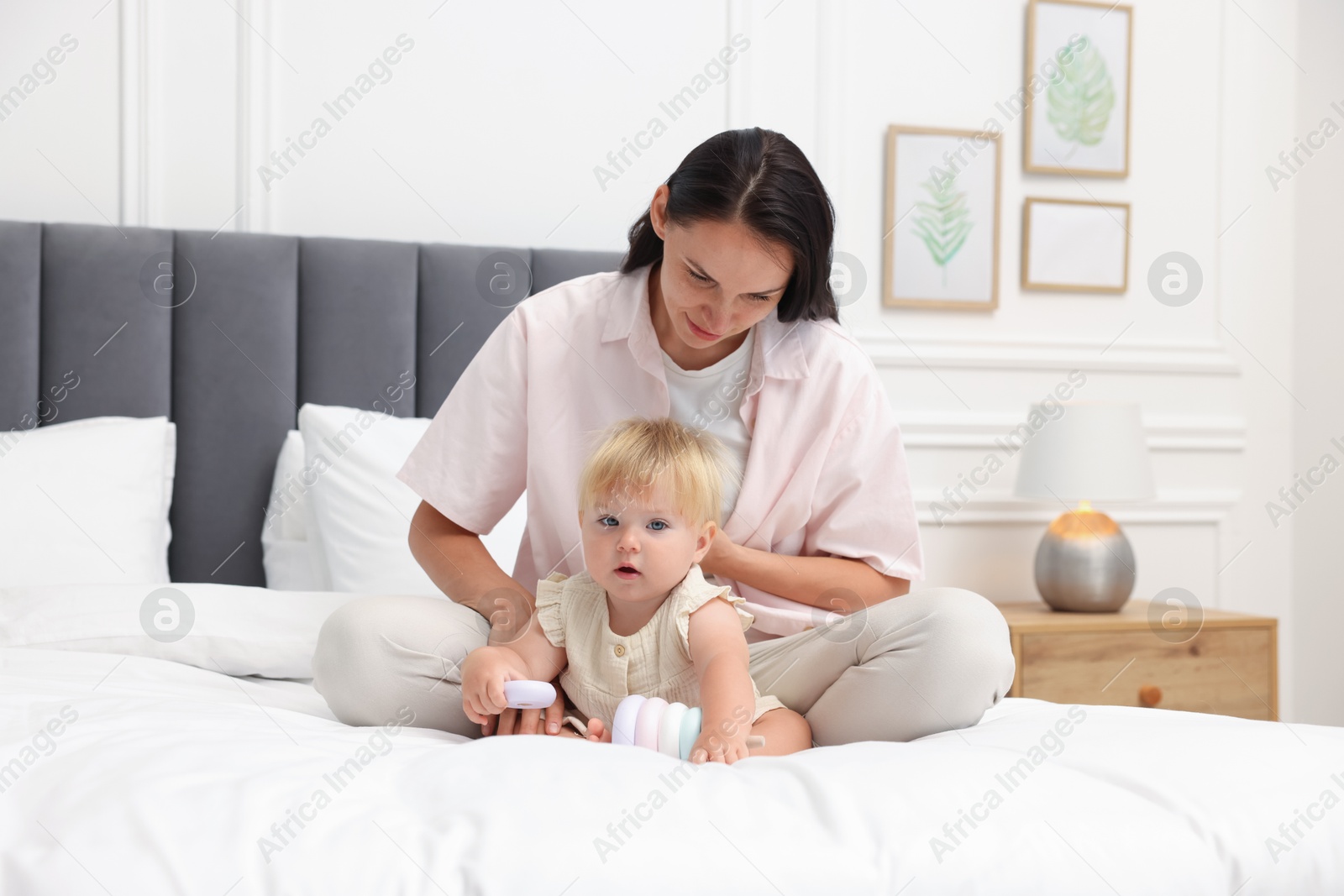 Mother playing with her cute baby girl on bed at home Photo of Mother playing with her cute baby girl on bed at home