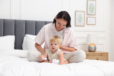 Photo of Mother playing with her cute baby girl on bed at home