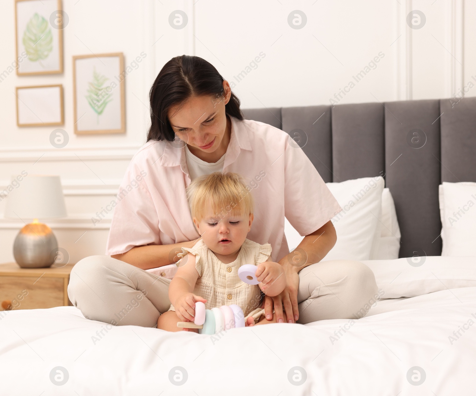 Mother playing with her cute baby girl on bed at home Photo of Mother playing with her cute baby girl on bed at home