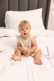 Photo of Cute baby girl in dress playing on bed at home