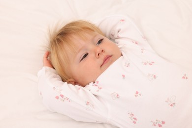 Photo of Cute baby lying on bed at home, closeup