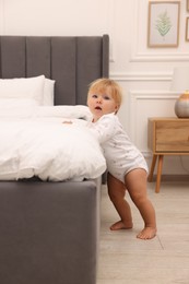 Photo of Cute baby leaning on bed at home