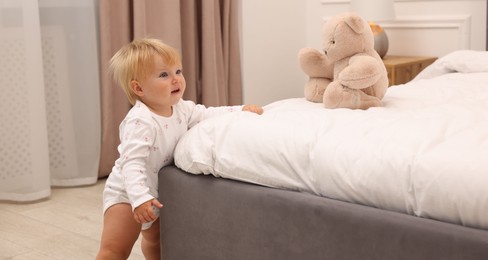 Photo of Cute baby leaning on bed at home
