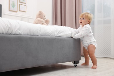 Photo of Cute baby leaning on bed at home
