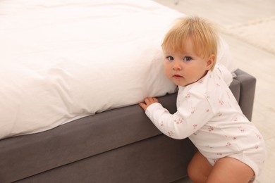 Photo of Cute baby leaning on bed at home