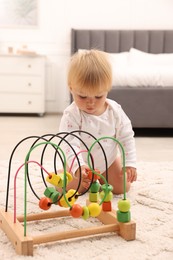 Photo of Cute baby playing with toy on floor at home