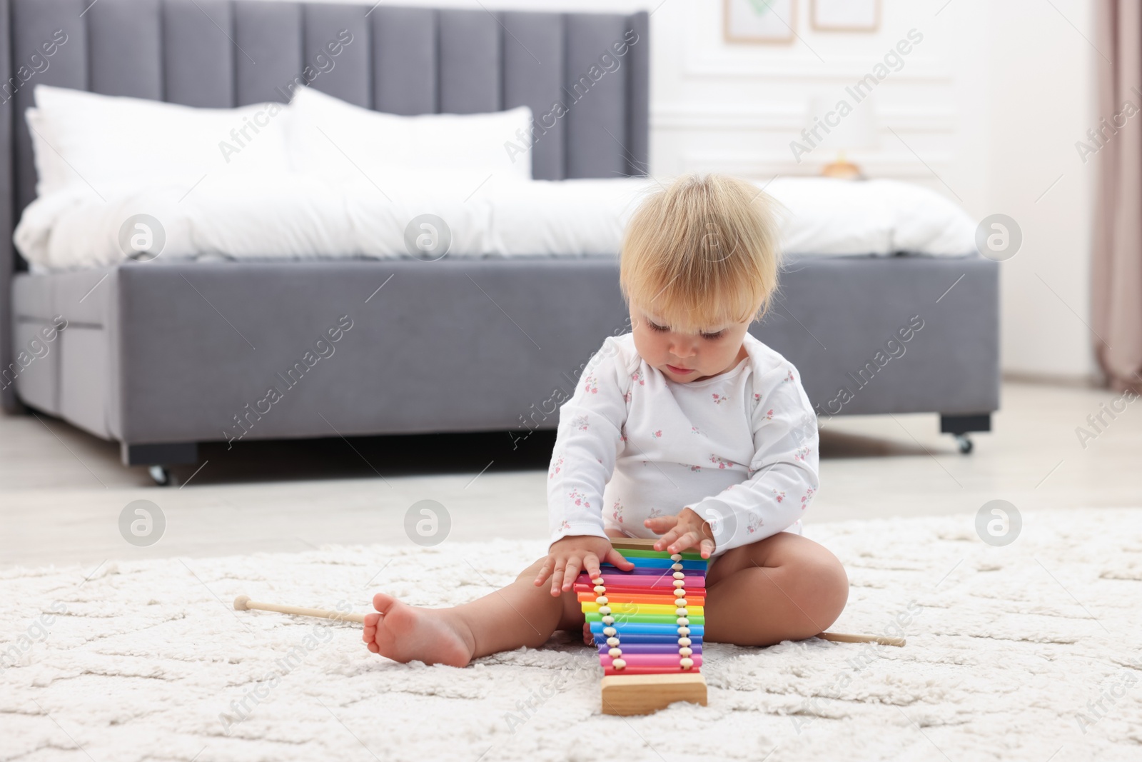 Cute baby playing with toy xylophone on floor at home Photo of Cute baby playing with toy xylophone on floor at home