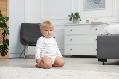 Photo of Cute baby sitting on floor at home