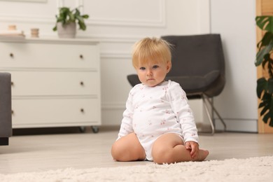 Photo of Cute baby sitting on floor at home. Space for text