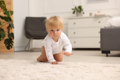 Photo of Cute baby crawling on floor at home