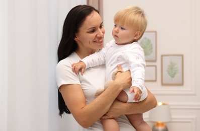 Photo of Smiling mother hugging her cute baby at home