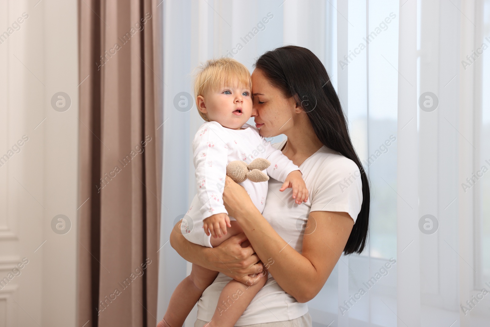 Mother with her cute baby near window at home Photo of Mother with her cute baby near window at home