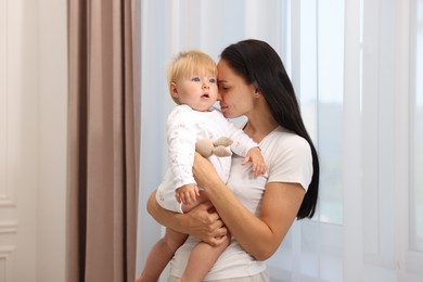Photo of Mother with her cute baby near window at home