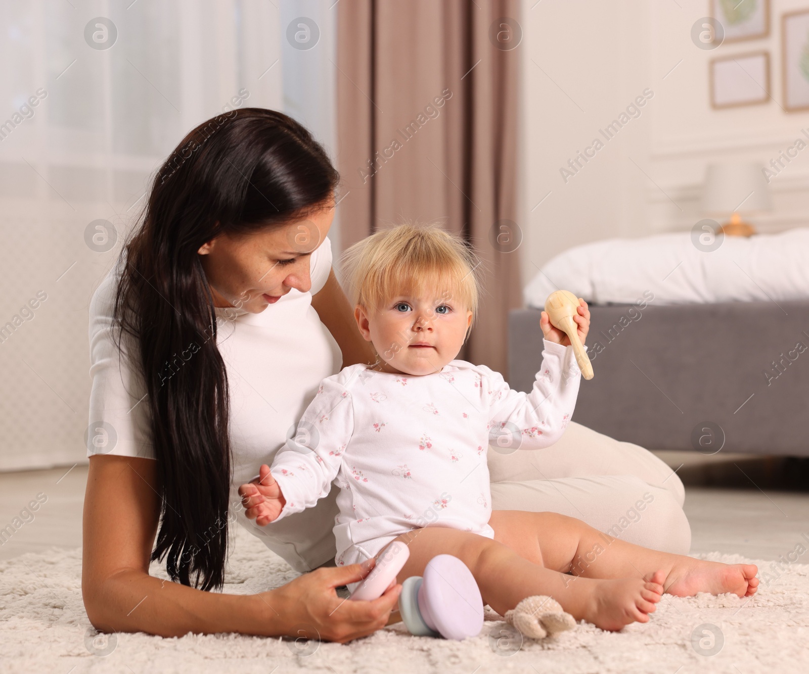 Mother playing with her cute baby on floor at home Photo of Mother playing with her cute baby on floor at home