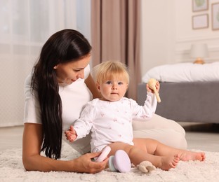 Photo of Mother playing with her cute baby on floor at home