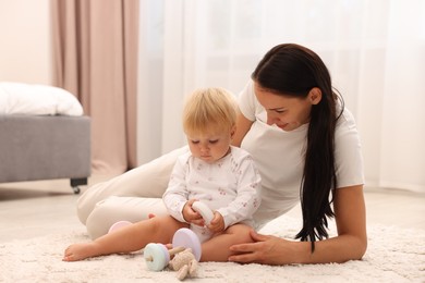 Photo of Mother playing with her cute baby on floor at home
