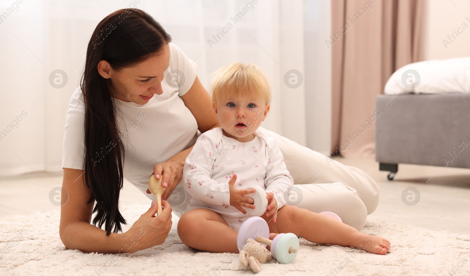 Smiling mother playing with her cute baby on floor at home Photo of Smiling mother playing with her cute baby on floor at home