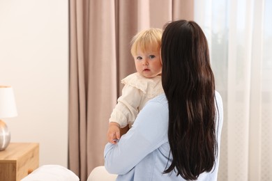 Photo of Cute baby with her mother at home, back view. Space for text