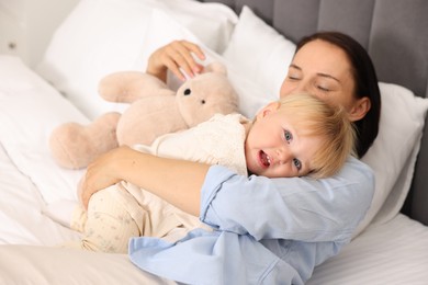 Photo of Cute baby girl and her mother on bed