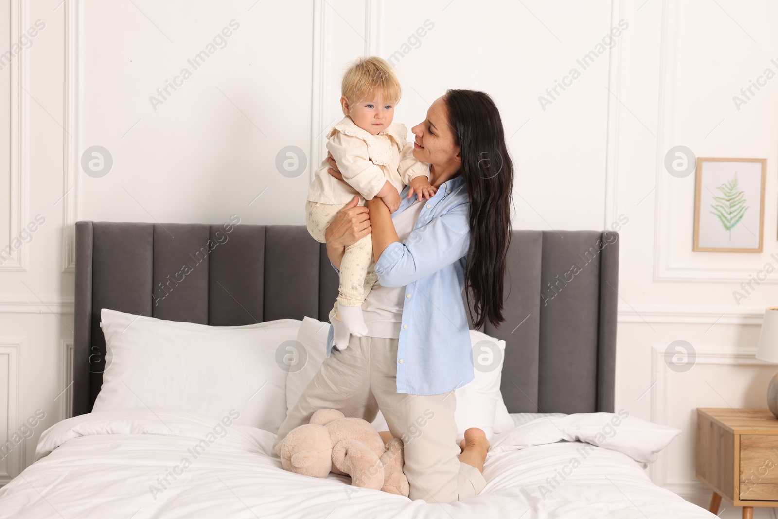 Smiling mother with her cute baby on bed at home Photo of Smiling mother with her cute baby on bed at home