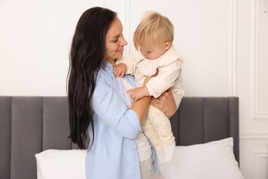 Photo of Smiling mother with her cute baby on bed at home