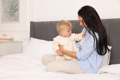 Photo of Mother with her cute baby sitting on bed at home. Space for text
