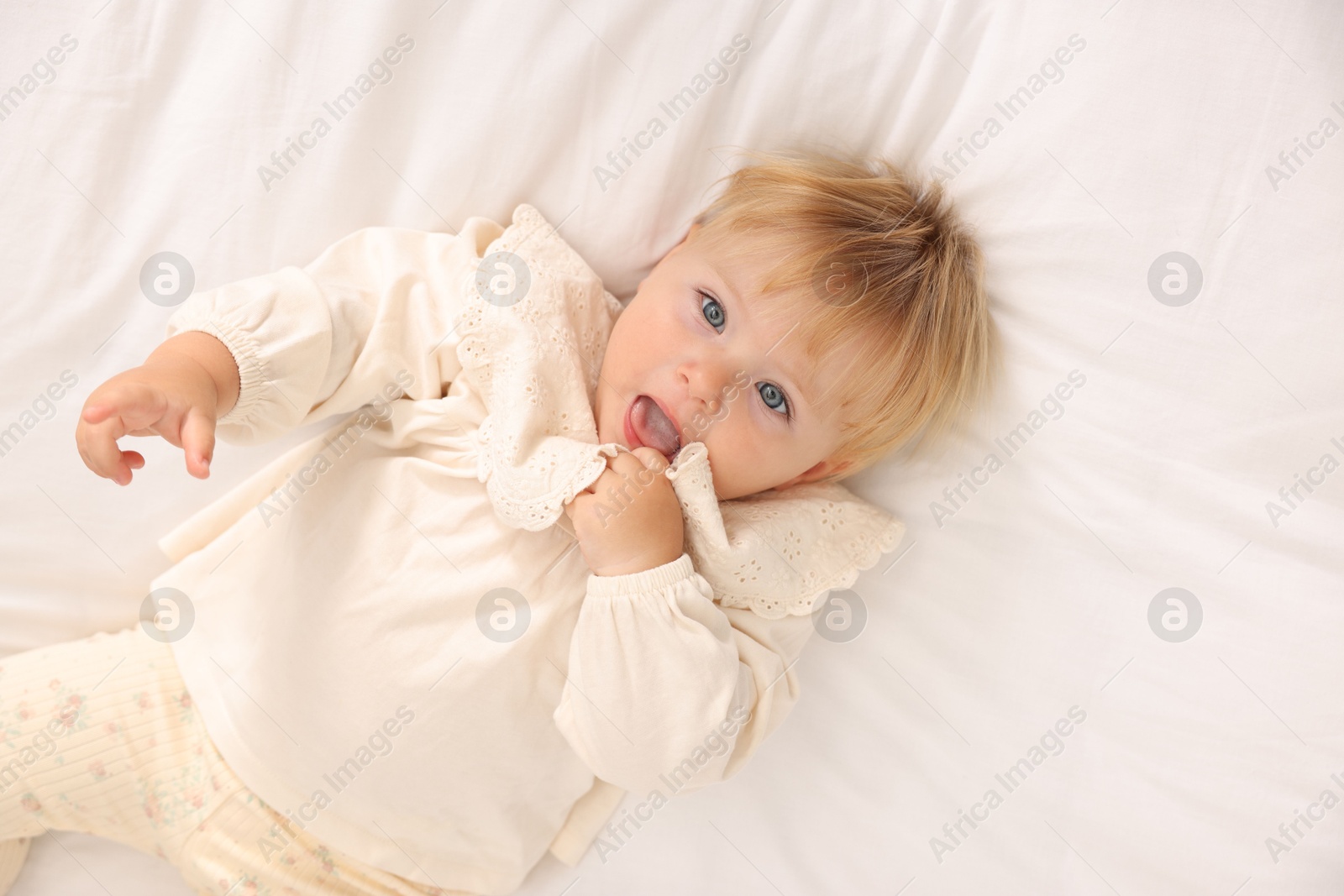 Photo of Cute baby lying on white blanket, top view
