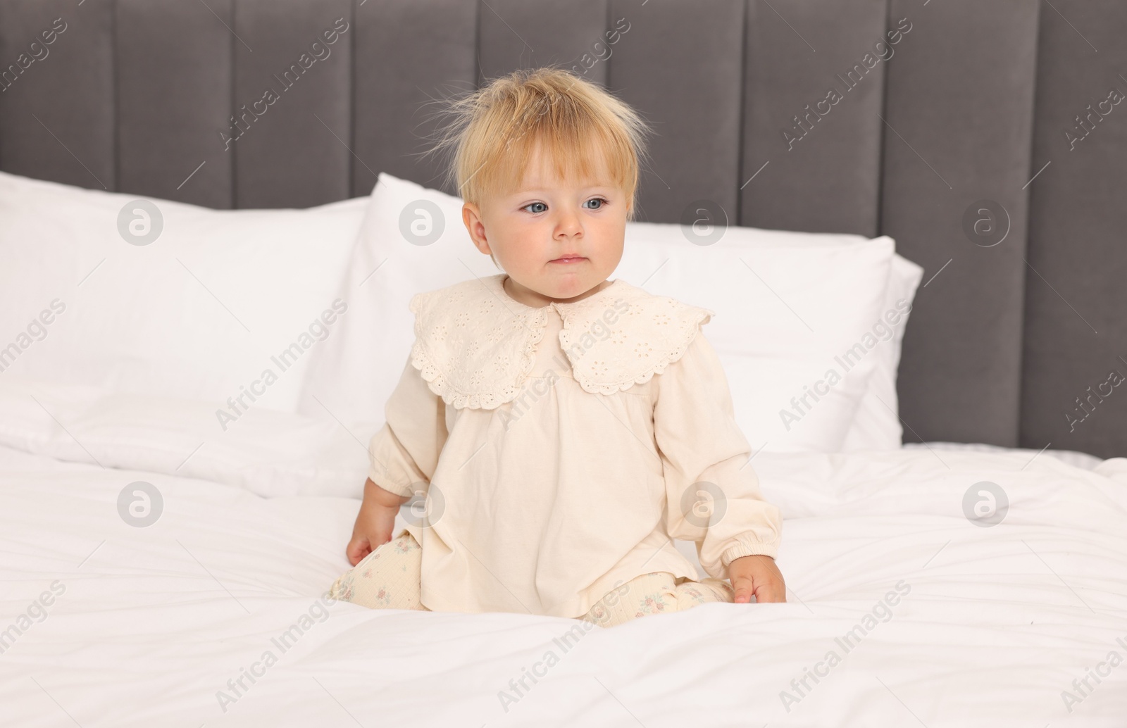 Photo of Cute baby sitting on bed at home