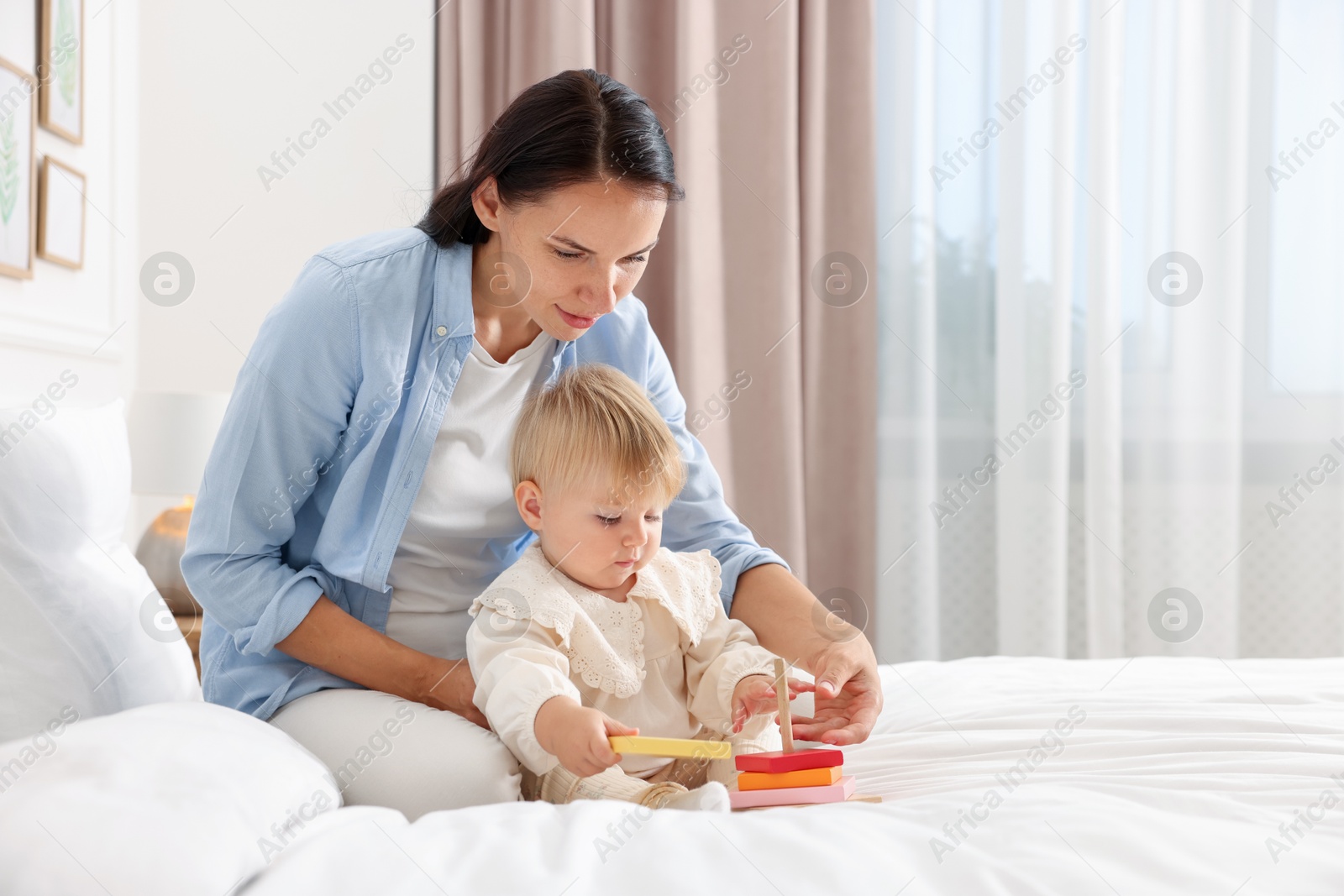 Mother with her cute baby playing on bed at home. Space for text Photo of Mother with her cute baby playing on bed at home. Space for text