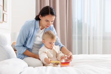 Photo of Mother with her cute baby playing on bed at home. Space for text