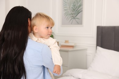 Photo of Cute baby with her mother at home, back view. Space for text