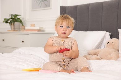Photo of Cute baby with toy sitting on bed at home