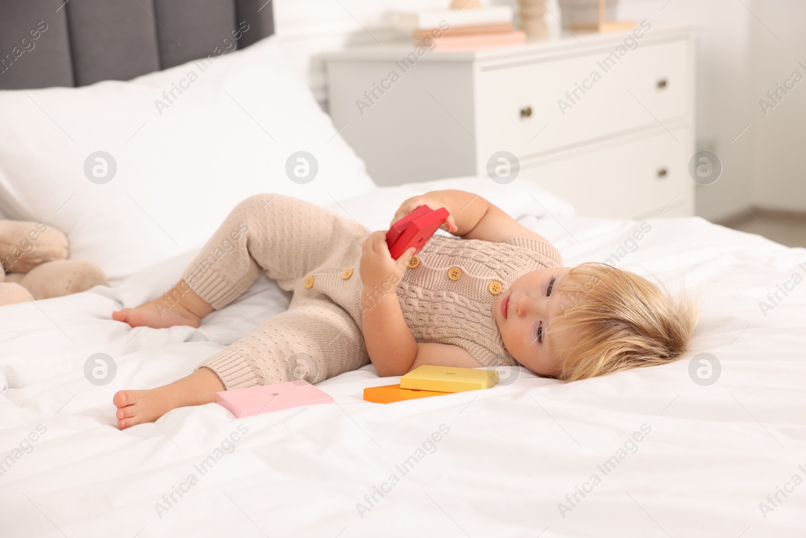 Cute baby with toy lying on bed at home Photo of Cute baby with toy lying on bed at home