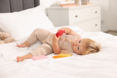 Photo of Cute baby with toy lying on bed at home