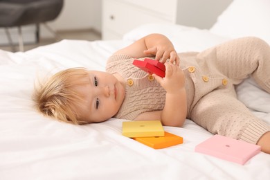 Photo of Cute baby with toy lying on bed at home