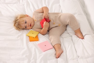 Photo of Cute baby with toys lying on white blanket