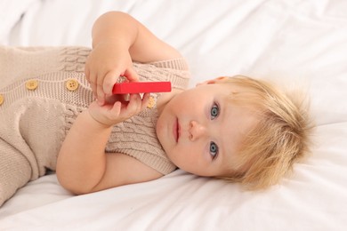 Photo of Portrait of cute baby with toy lying on white blanket, closeup