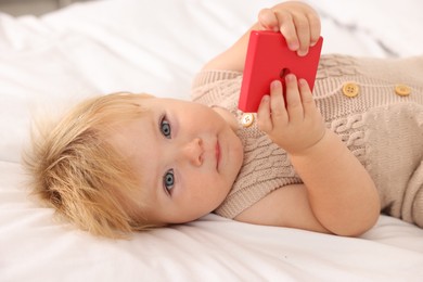 Photo of Portrait of cute baby with toy lying on white blanket, closeup