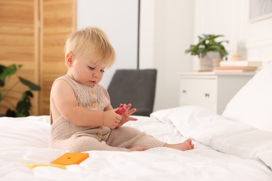 Photo of Cute baby with toy sitting on bed at home