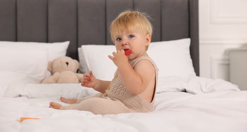 Photo of Cute baby with toy sitting on bed at home