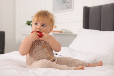 Photo of Cute baby with toy sitting on bed at home