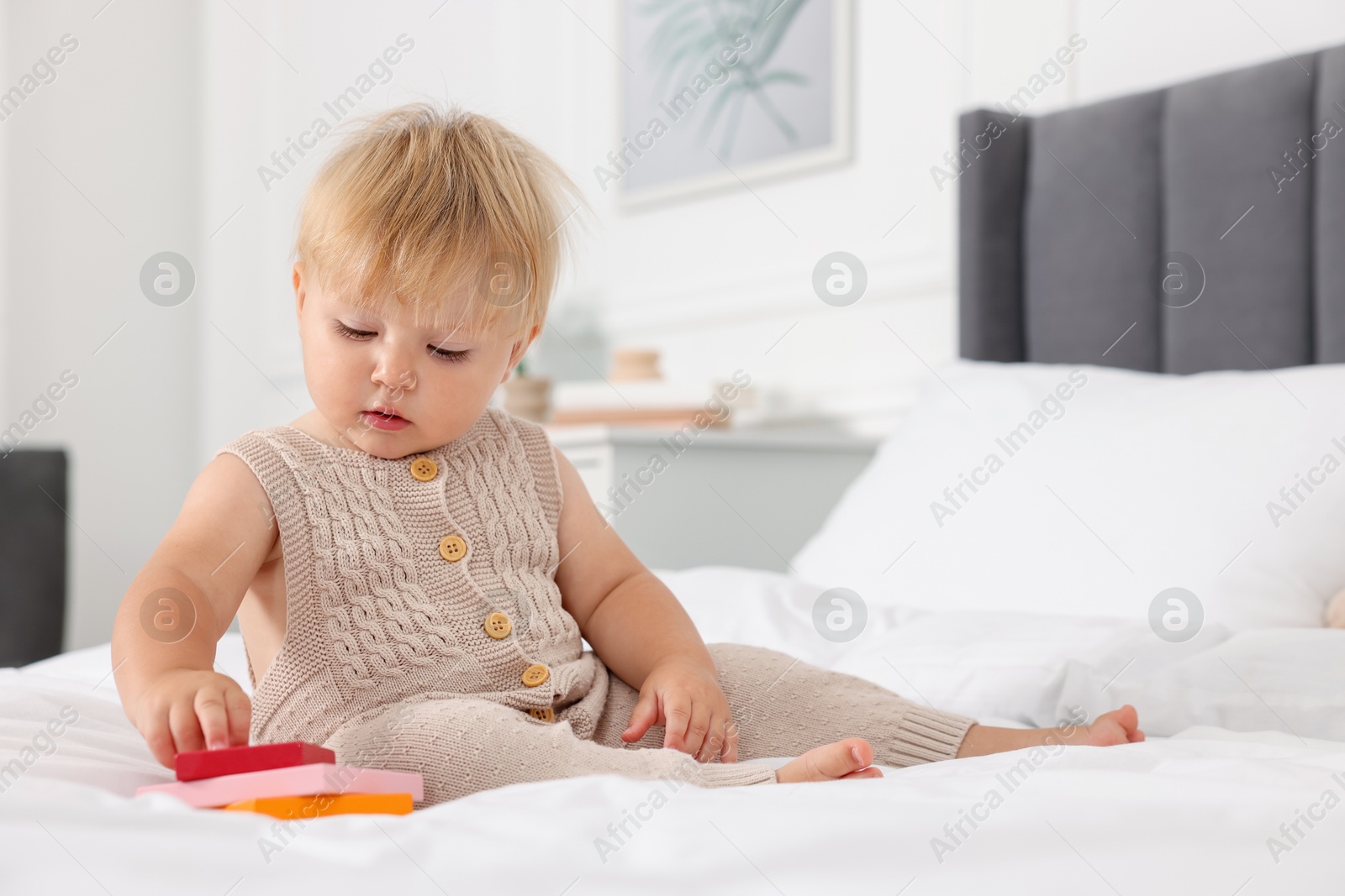 Cute baby with toy sitting on bed at home Photo of Cute baby with toy sitting on bed at home