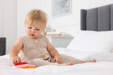 Photo of Cute baby with toy sitting on bed at home