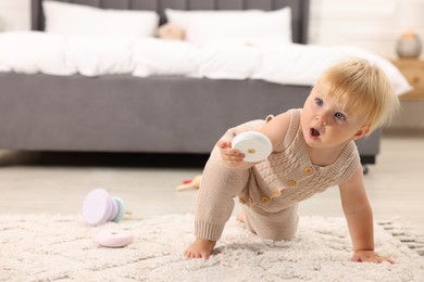 Photo of Cute baby with toy on floor at home. Space for text