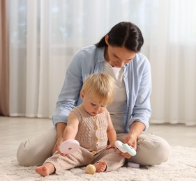 Photo of Mother with her cute baby playing on floor at home