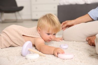 Photo of Cute baby and her mother playing on floor at home, closeup